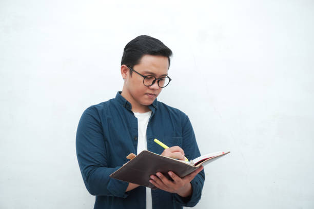 istock Young Asian man holding books while thinking and concentrating. 2162738007