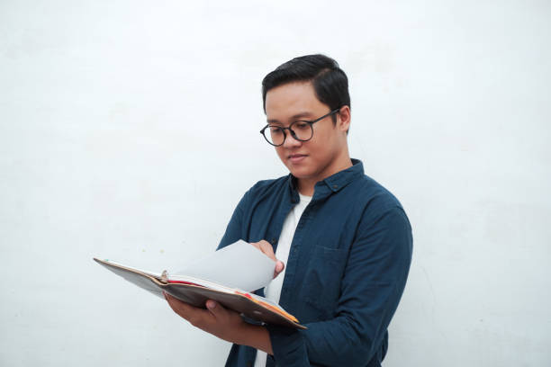 istock Young Asian man holding books while thinking and concentrating. 2162738034