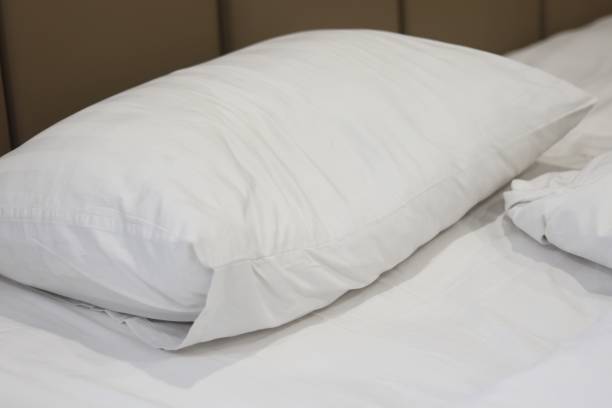 istock close-up of white bed sheets and pillows in hotel. 2162738490