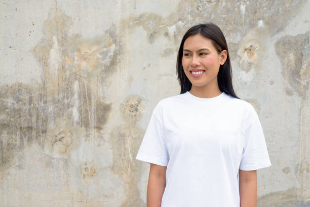 istock Young Thai Woman Smiling Outdoors Against Wall Background 2162738648