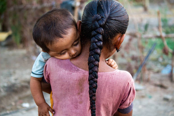 Protective Sister Carrying Sleeping Baby in Rural Setting