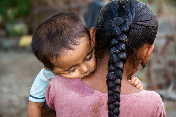 istock Protective Sister Carrying Sleeping Baby in Rural Setting 2162742025