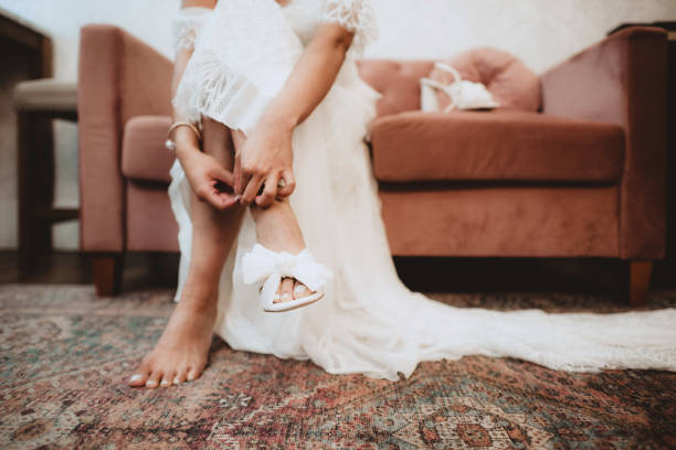 Beautiful woman putting on shoes with painted toenails