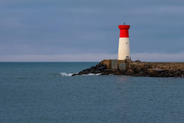 istock A lighthouse is on a rocky shoreline 2162747212