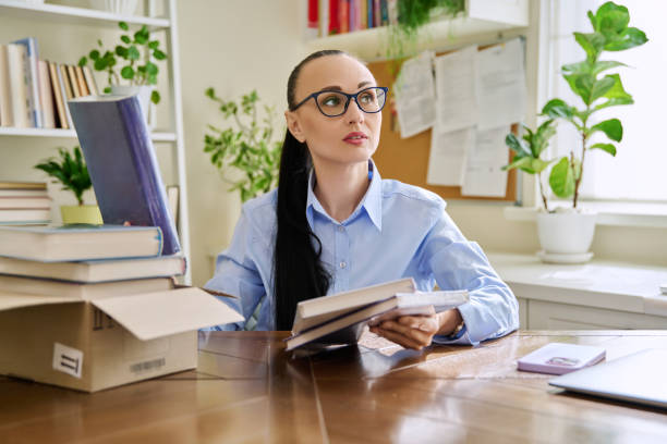 istock Woman with new books unpacked from cardboard box 2162754750