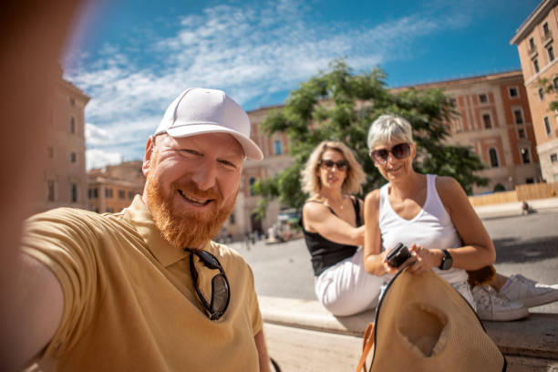 A small group of three mature tourist friends made up of 2 beautiful women and a redhead man enjoying a sightseeing day in Rome, Italy