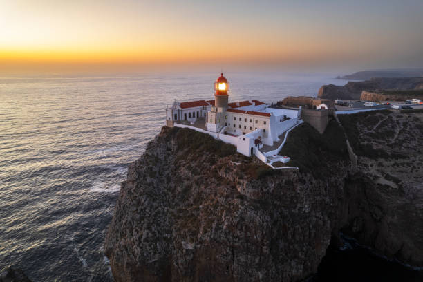 Aerial shot of the lighthouse on top of a rugged cliff seen at dusk, Vila do Bispo, Algarve, Portugal, Southern Europe, Europe