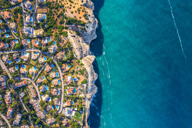 Aerial view of whitewashed houses with red tiles rooftops against the mediterranean sea in the city of Roses, on the Costa brava