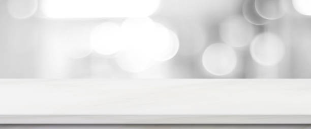 istock Empty white table top, counter, desk over blur perspective monochrome store with bokeh light background, White marble stone table, shelf and blurred shop for food, product display mockup, template backdrop, banner, Retail business wallpaper, poster 2162763553