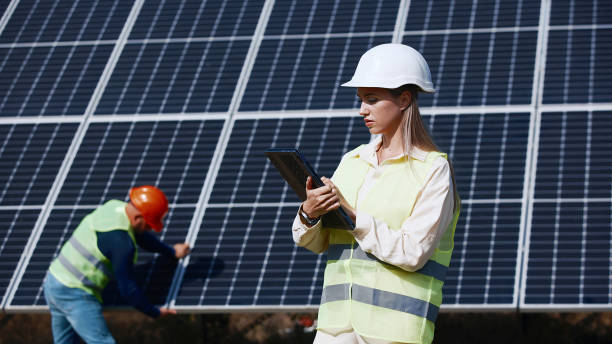istock Female ecological engineer uses project documents and files and collects efficient information about solar panels. Photovoltaic solar farm. Green energy. Environment. Concept of green energy 2162775967
