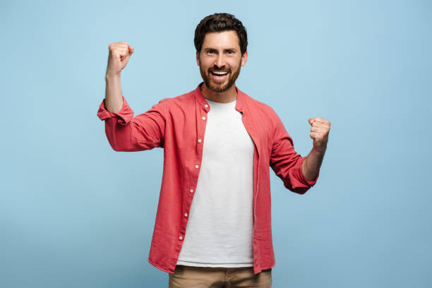 istock Happy young Caucasian man doing winner gesture while looking at camera, posing in studio 2162776514