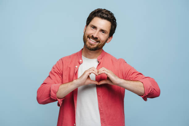 istock Smiling young man doing heart symbol shape with hands, looking at camera, isolated 2162776529