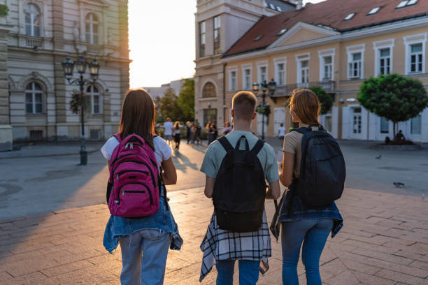istock Back view of three students with backpacks walking away 2162783955