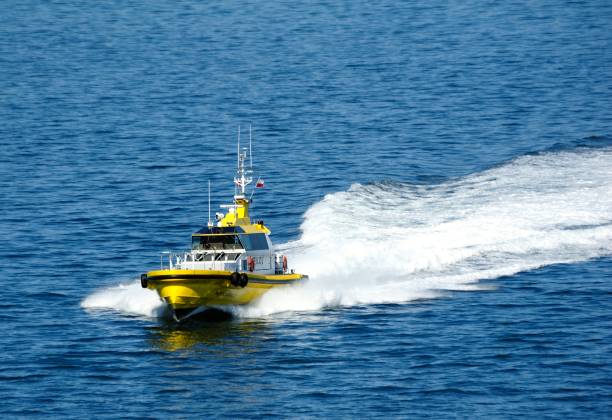 Angular full view of yellow and white pilot boat with dark blue ocean in background