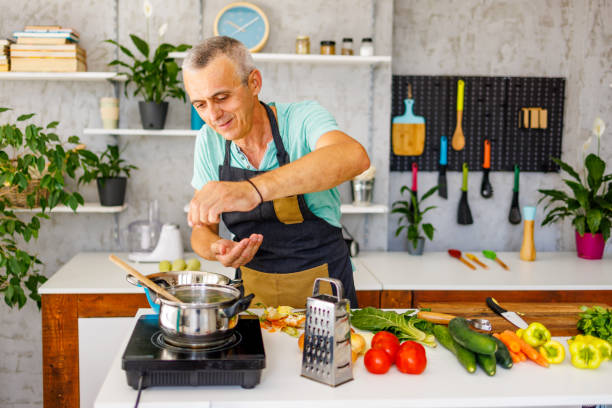 istock Smiling man puts spices in soup 2162785195