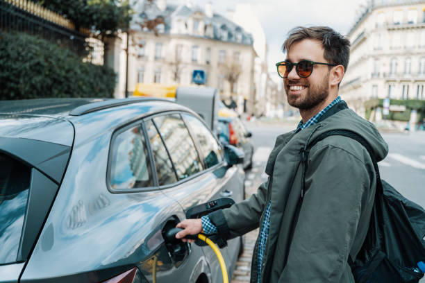 Young millennial man charging electric vehicle