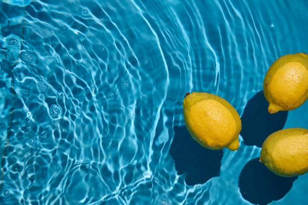 istock Bright yellow lemons floating in blue water 2162786415