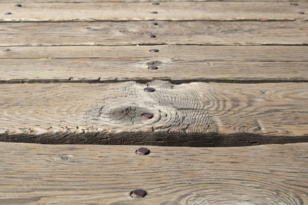 Low angle view of weathered and old outdoor wood flooring. Boardwalk, deck or patio texture. Selective focus.