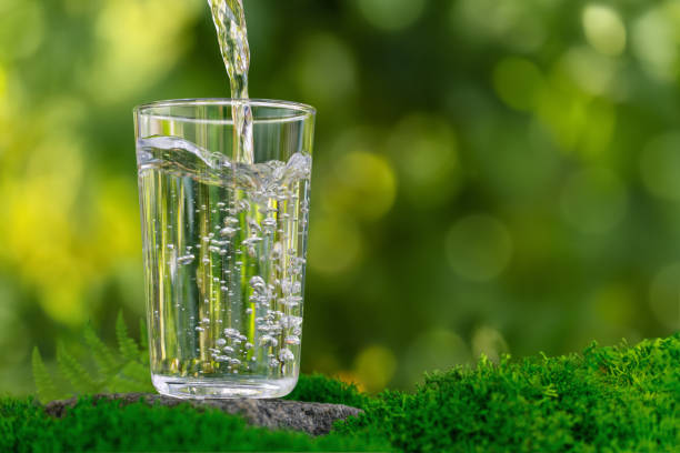 istock water pouring into glass on rock with moss 2162794638