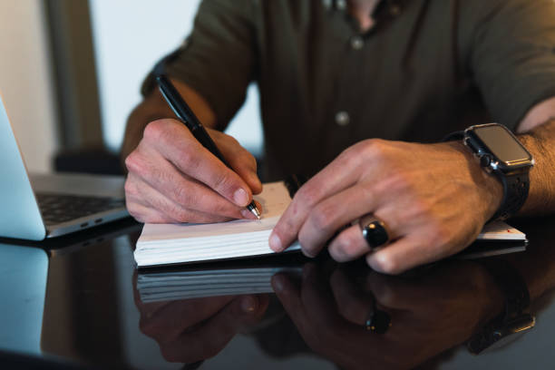 istock Anonymous man writing in notebook near laptop 2162795479