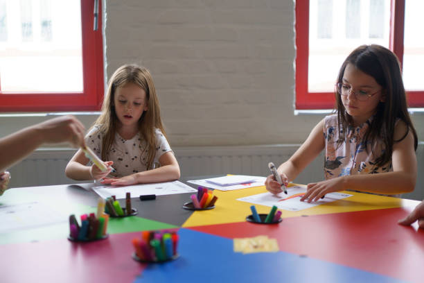 istock Two little beautiful girls are sitting at a table doing creative work at school. Children's education concept 2162806733