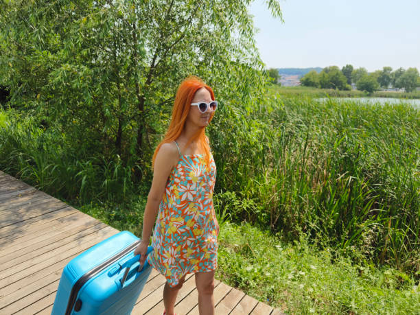 Female tourist pulling her luggage in suitcase and looking around European city