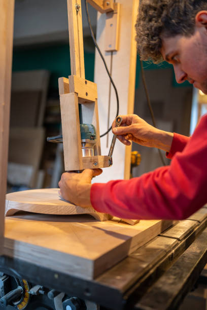 istock Attentive carpenter sets up milling machine. Careful man tightens tool with spanner 2162817938