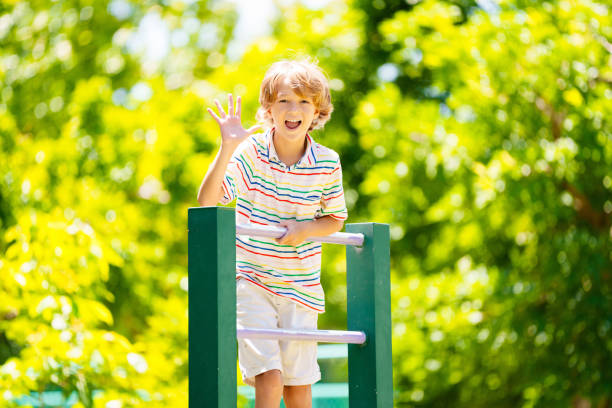 Child on playground. Active kid exercising in school yard. Children play and climb. Little boy on monkey bars. Kids having fun on sunny summer day in beautiful park.