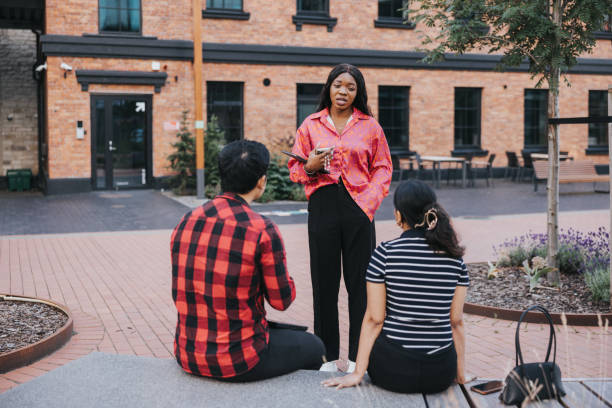 istock Three young colleagues are seated on a bench in front of their office building, having a quick meeting 2162820959