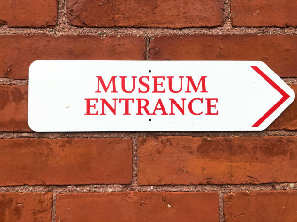 White Arrow Sign on Brick Reading: Museum Entrance