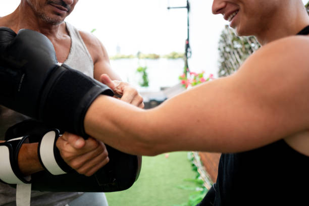 istock Personal trainer helping young boxer putting on boxing gloves for training session 2162832357