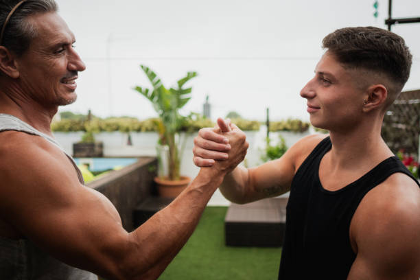 Two male athletes shaking hands on a rooftop after outdoor workout