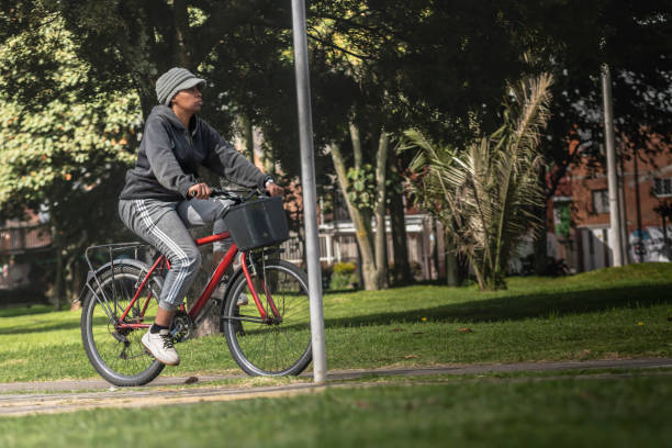 Bogota Colombia 22 de junio de 2024: Afro woman to work on her bicycle, green, tree