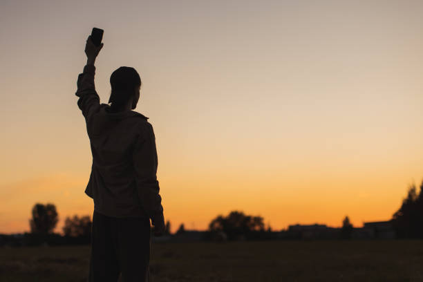 istock Male silhouette against sunset background. Mobile phone in hand. 2162840891