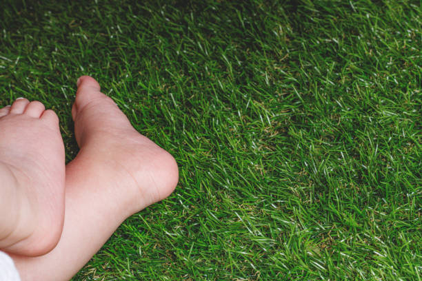 A child enjoys the simple pleasure of walking barefoot on fresh green grass. A moment of connection with nature, feeling the texture, temperature, and energy of the earth beneath their feet.