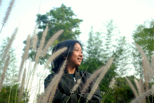 Beautiful young girl wearing blank gray t-shirt and black jeans posing against high green and yellow grass in early warm autumn. Outdoor portrait of beautiful female model.