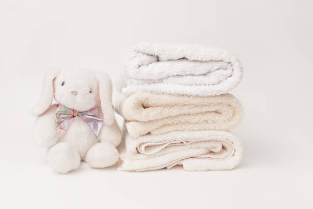 istock Bunny fluffy toy with clean baby beige soft bath towels stack on a white background 2162853476