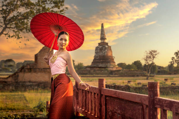 Young Woman in Lanna Thai Costume Holding a Handmade Umbrella Outdoors