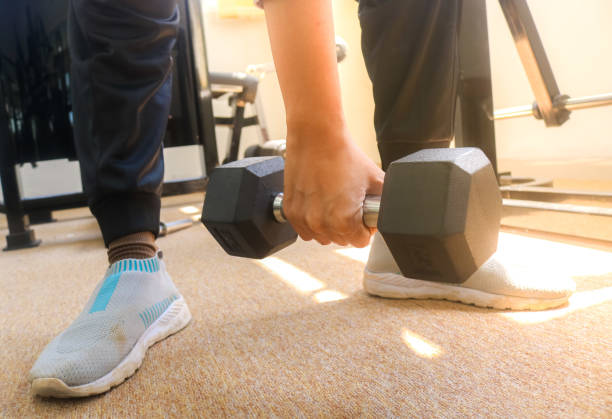 istock Woman's hand holding a 5 kilogram dumbbell with one hand with sunlight. Training arm muscles with dumbbells 2162856936