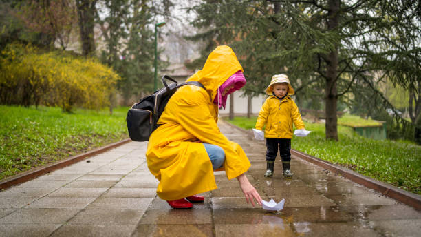 istock It's springtime. A small child in rubber boots jumps through puddles, plays and launches paper boats on the water. 2162858037