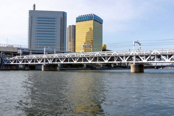 Tokyo, Japan- 11 May 2024: Railway bridge across Sumida river at Sumida River Walk park in Tokyo, Japan. Sumida River Walk is a structured way of seeing the attractions by the side of the river