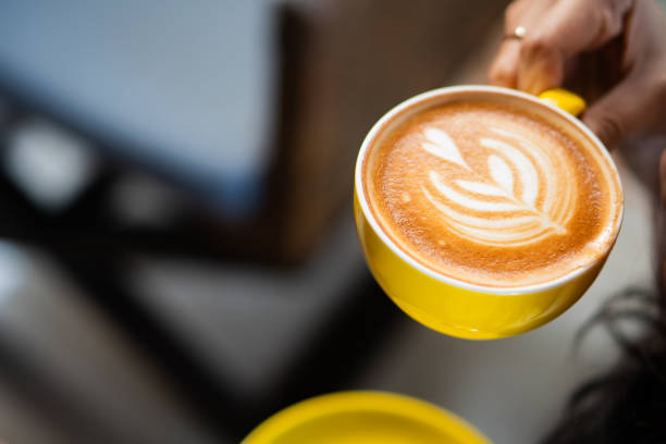 istock Hand Holding Yellow Coffee Cup with Latte Art 2162861197