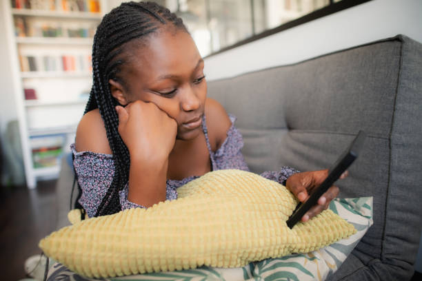 istock Sad young woman with smartphone at home 2162861471