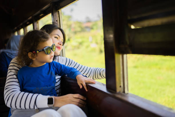 Young woman with her son looking out a window traveling on a train
