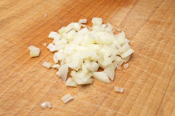 Onion cuts isolated, chopped white onion pile, vegetable small cubes on wooden board