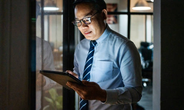 istock Businessman working late night with digital tablet in dimly lit office 2162867065