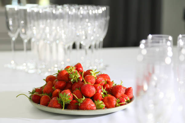 Strawberries in a plate on a white tablecloth. Strawberries in a round plate on a white table. Ripe and sweet gorgeous strawberries in a plate on a white tablecloth.