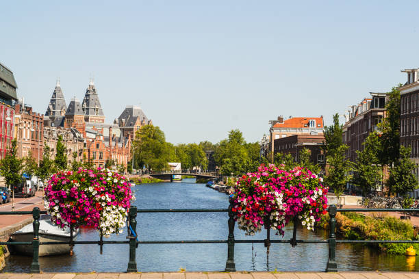 From the bridge you can see the canal with the typical Amsterdam houses. The city is full of beautiful flowers and the bridge, of course, is decorated with flowers. Varias barcas están amarás a lo largo del canal.
