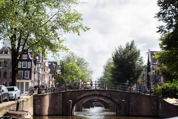 The Reguliersgracht canal is spanned by seven bridges (Nos. 31, 39, 40, 40, 72, 73, 74 and 81) which are best viewed from a boat, as you can see all seven at the same time. All seven are single arch bridges and at night they are illuminated, which adds to their romantic and almost magical character. Luminous day where several people with their bicycles ride along one of the bridges.