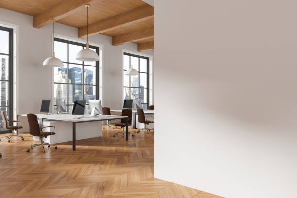 istock Modern office space with computers, chairs, and wooden flooring, blank white wall on the right, contemporary design. Empty workspace concept. 3D Rendering 2162869216